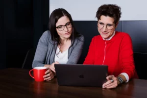 2 communita Mitarbeiterinnen sitzen vor einem Laptop und analysieren Google Ads Daten